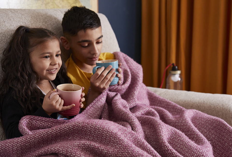 Children under blanket drinking hot chocolate