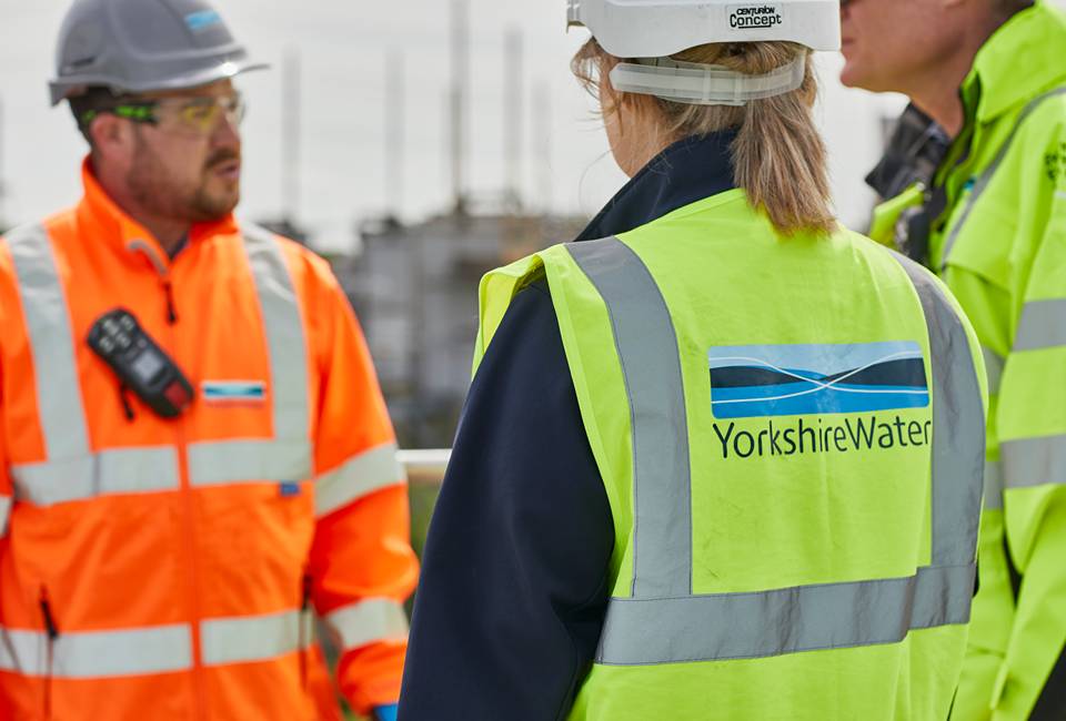 Three Yorkshire Water colleagues wearing high visibility jackets and helmets at a wastewater treatment works