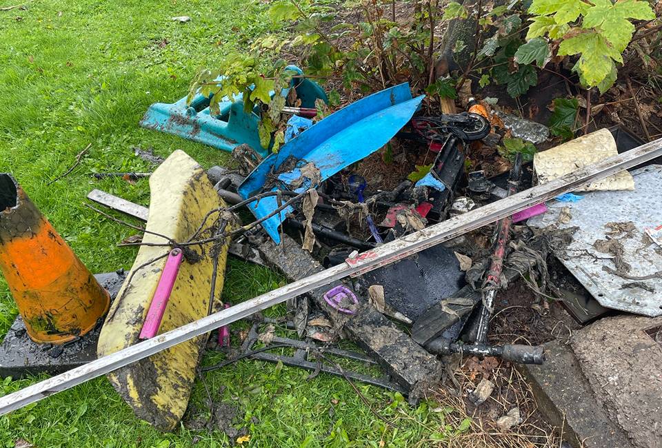 Scooters, a child's slide and other debris next to a tree after ebing removed from a sewer