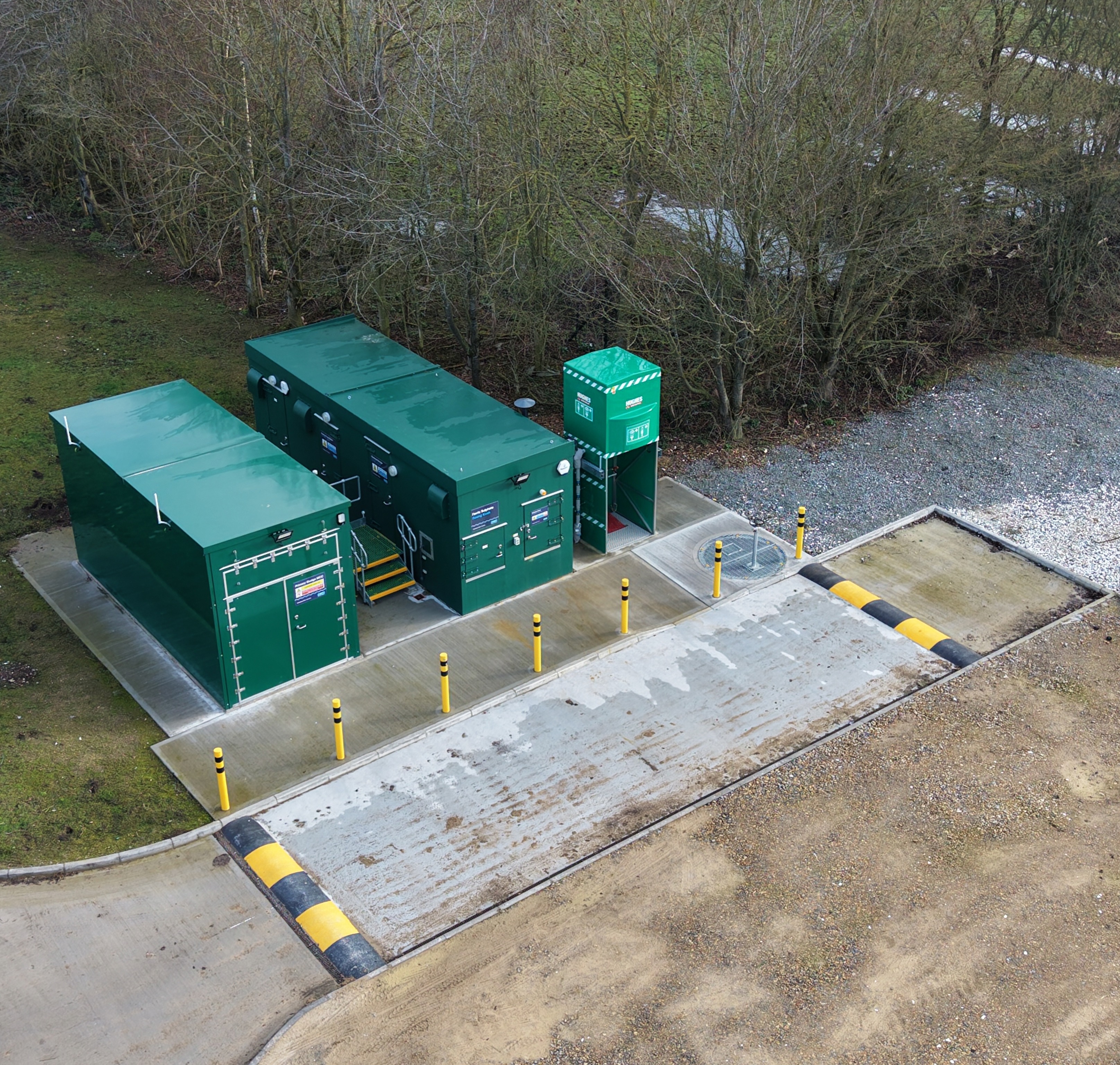 Aerial shot of 2 green rectangular buildings next to a short drive way