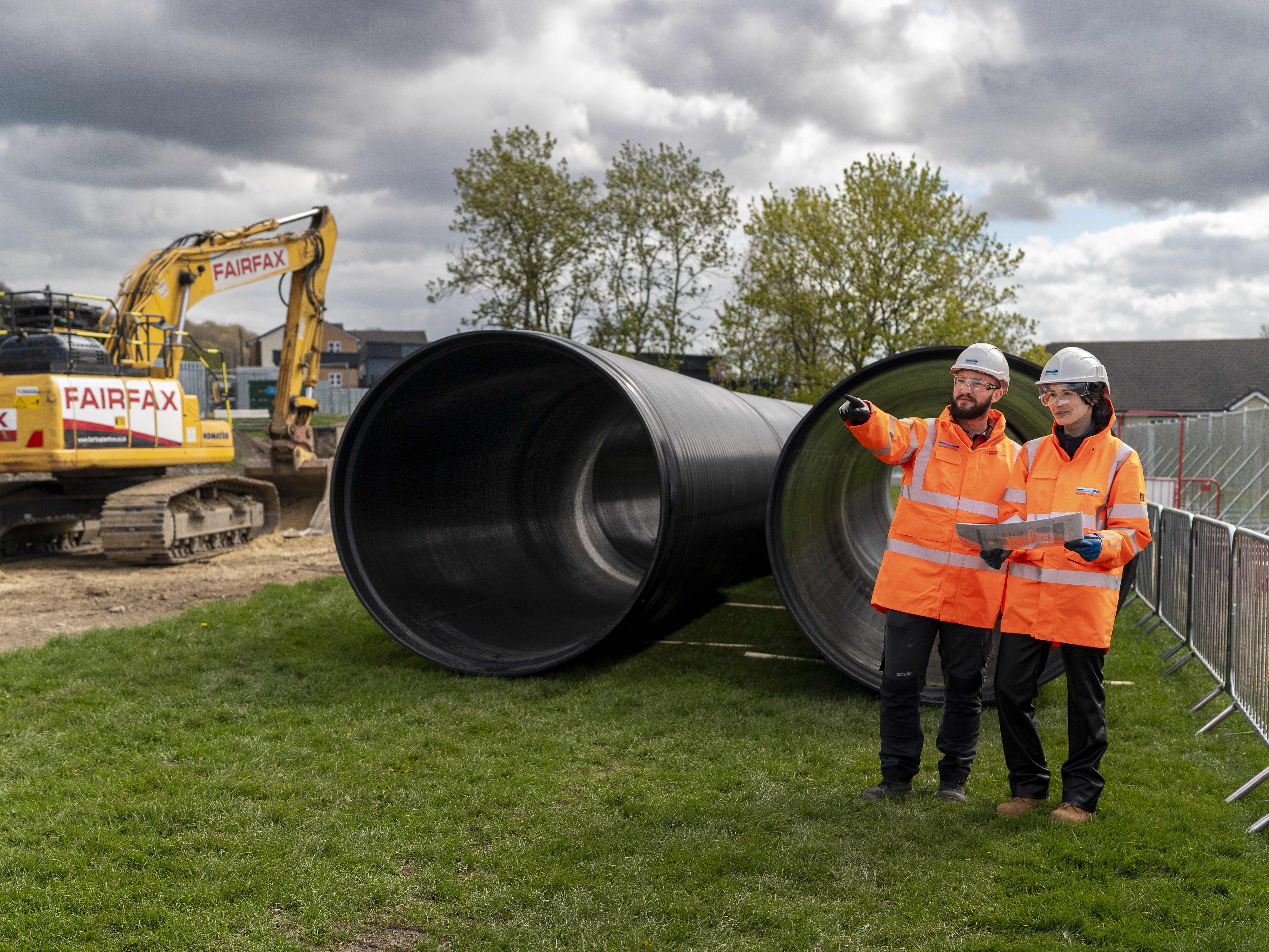 Very large pipe with two people in high vis and hard hats stood close by