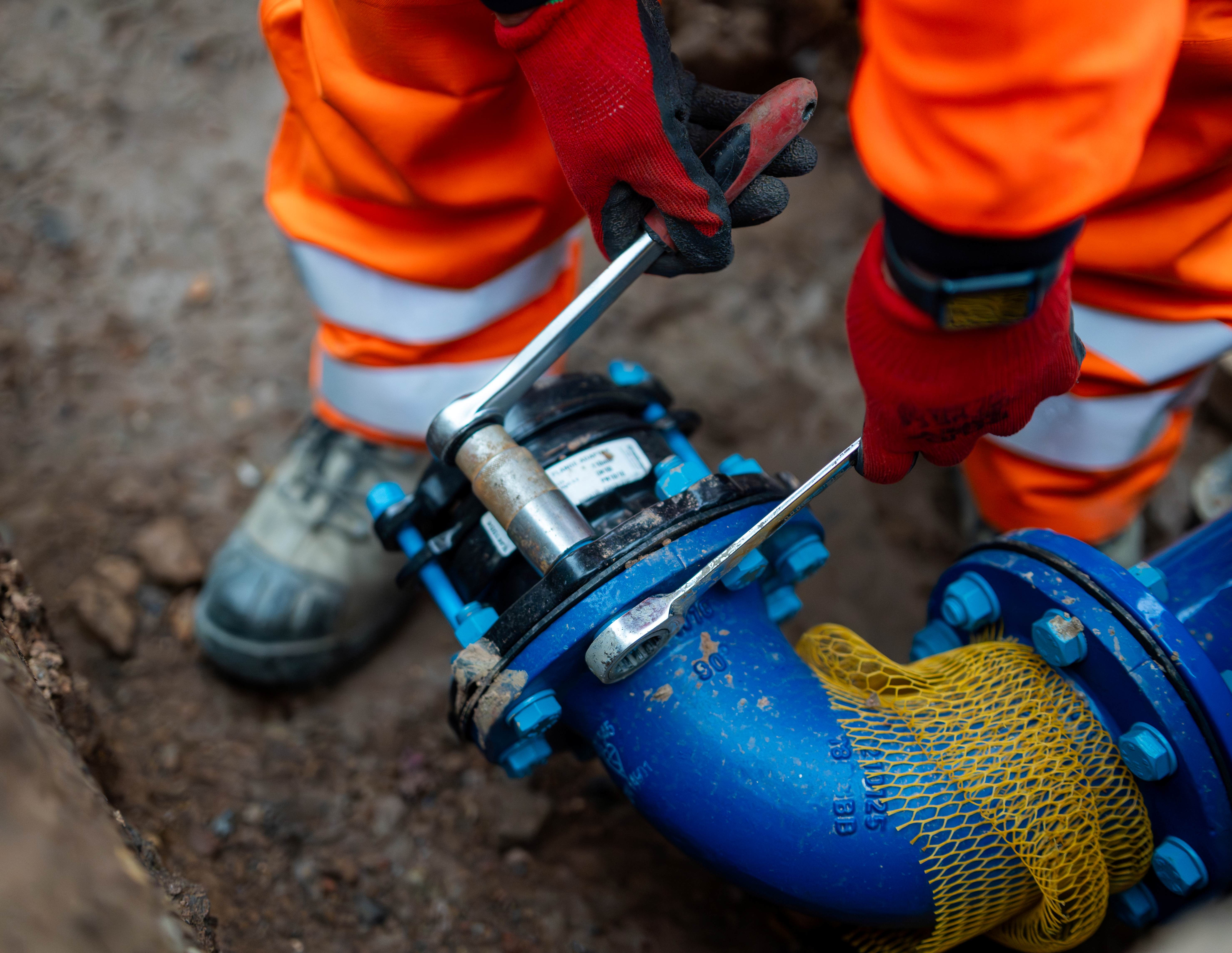 close up of work safety boots and person in high-vis managing a large pipe
