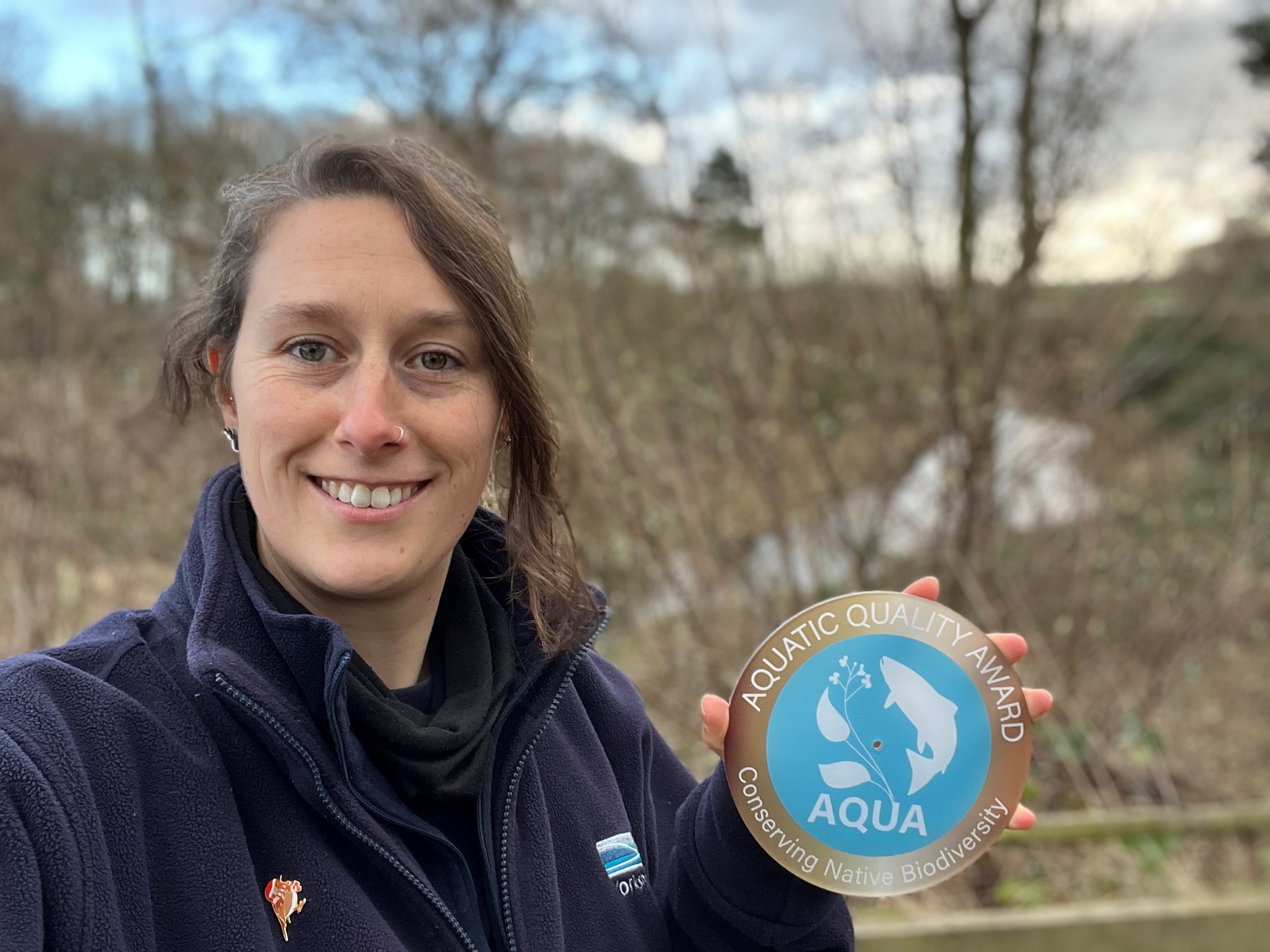 a photo of Amy Watsham holding the AQUA bronze accreditation plaque 