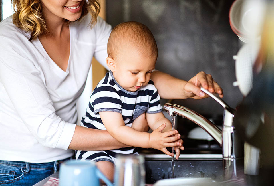 Mother and child using a kitchen tap