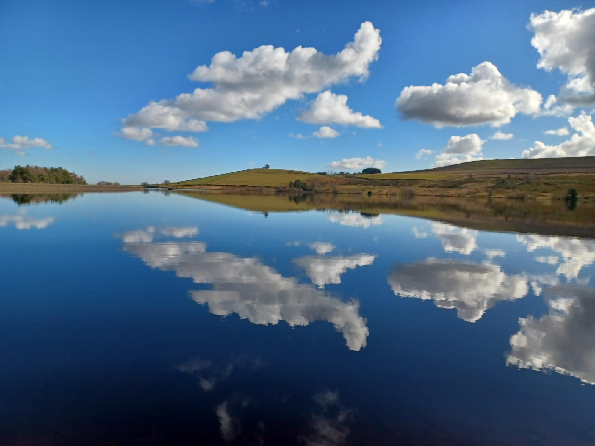 Image of Redmire Reservoir and blue lagoon lake and blue sky with white clouds reflected in the water