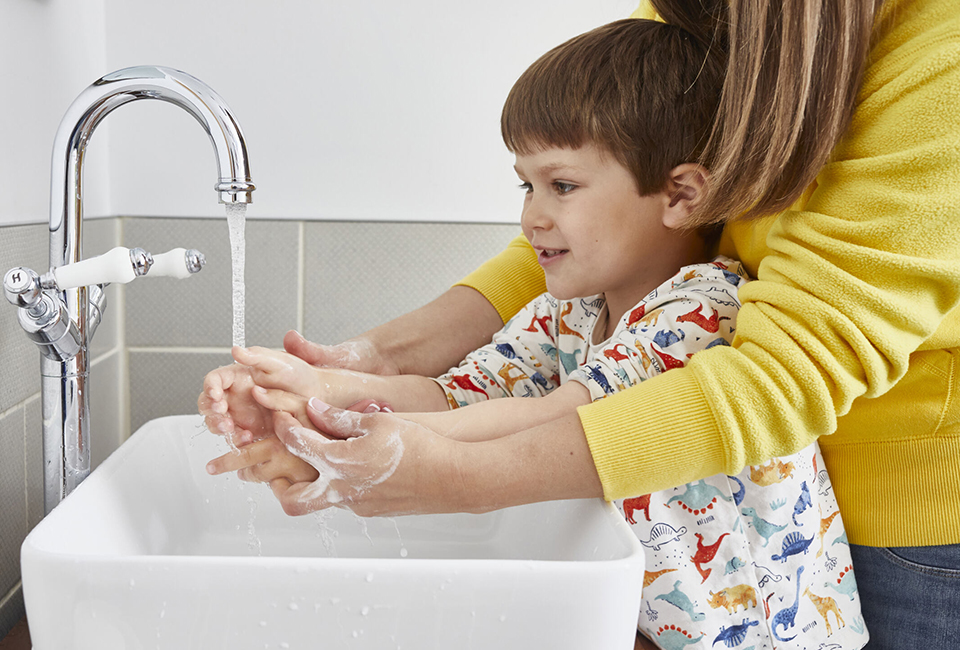 Mum helping child wash hands in bathroom
