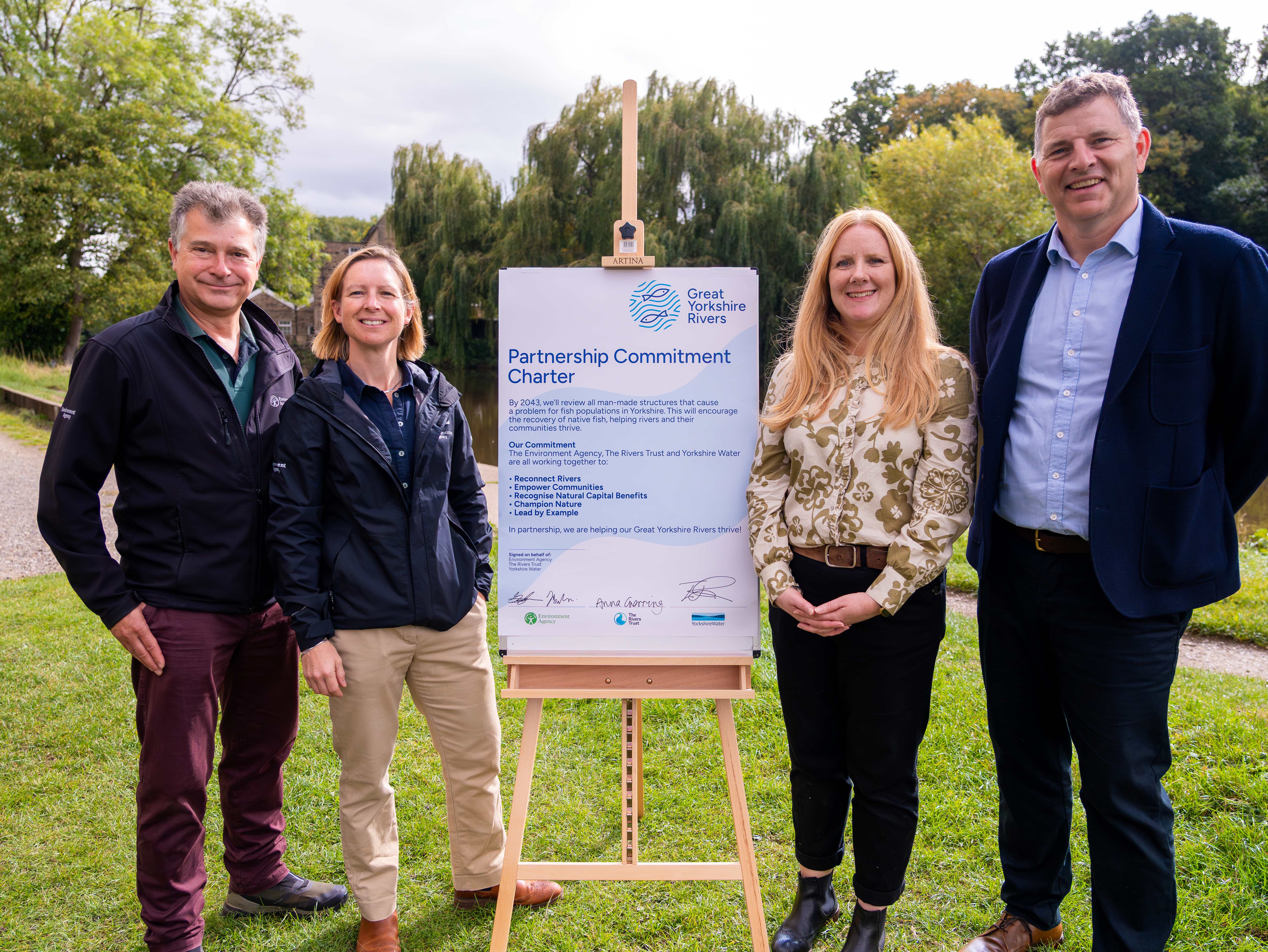four people stood by an easel with a large document attached