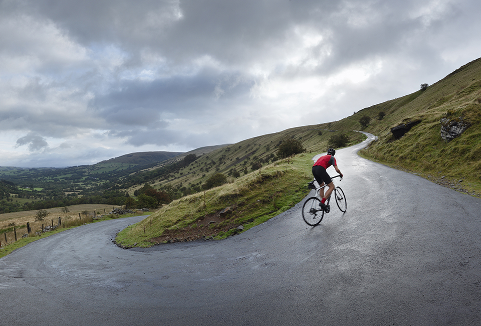 person cycling up a country road