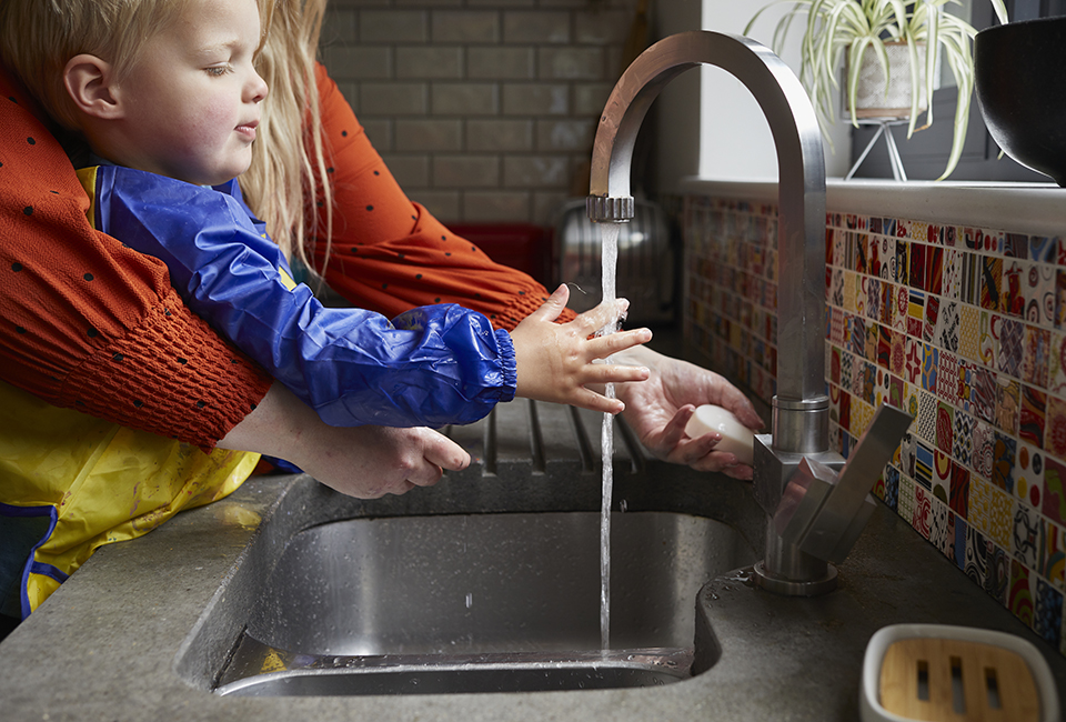 A mother helping a child wash their hands