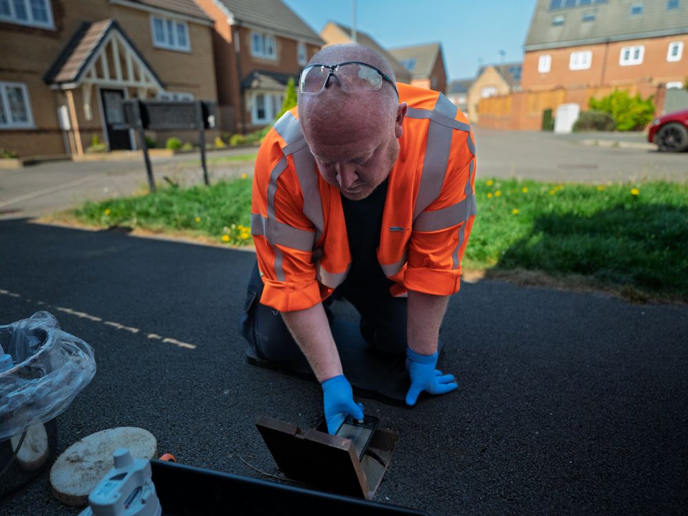 worker in high vis jacket knelt down to instal a smart meter