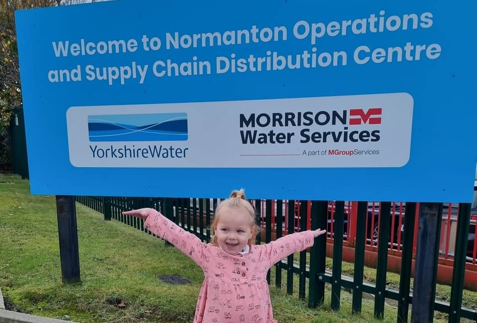 Young Yorkshire Water customer posing in front of sign for Normanton site