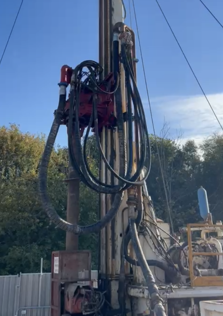 Heavy plant drill with trees and woodland in the background away from the site