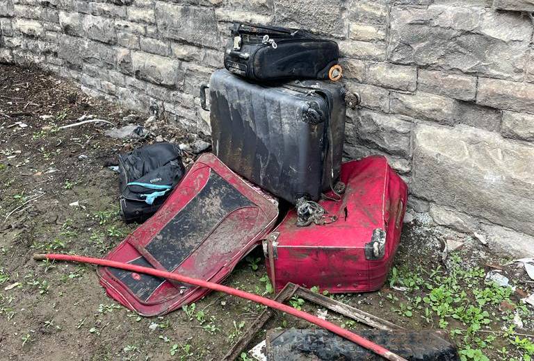 Four suitcases stood next to a wall after being removed from the sewer