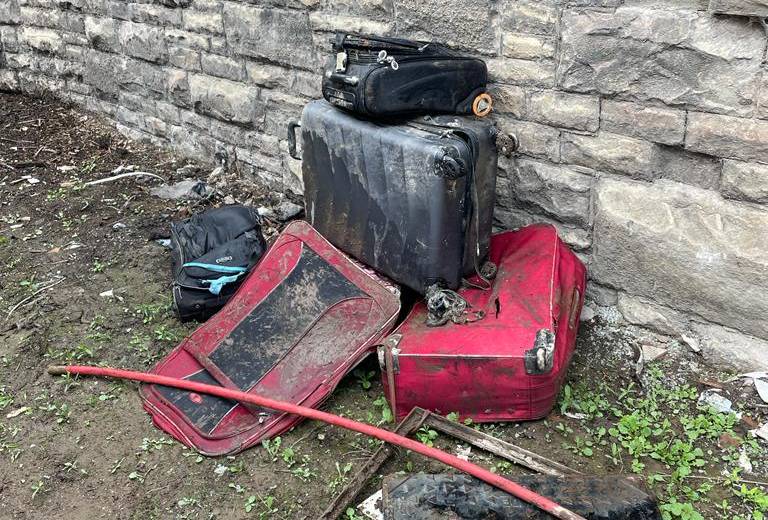 Four suitcases stood next to a wall after being removed from the sewer
