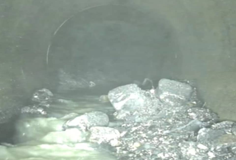 Image inside a sewer with debris and boulders blocking the sewer