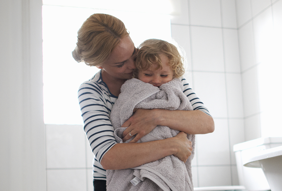 Mum wrapping child in towel after bath
