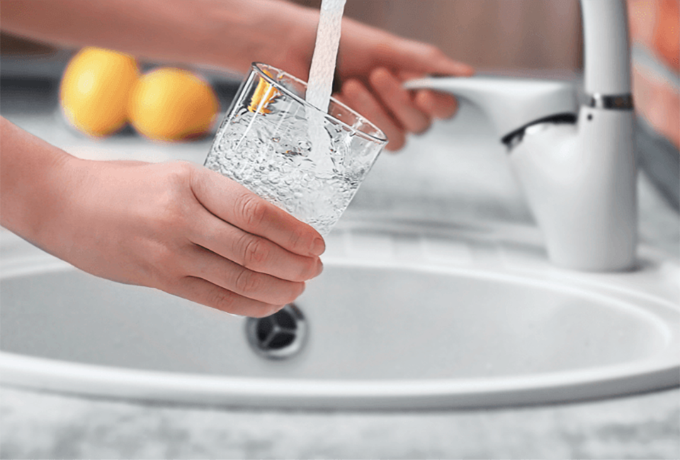 Person using a tap to fill a glass of water 